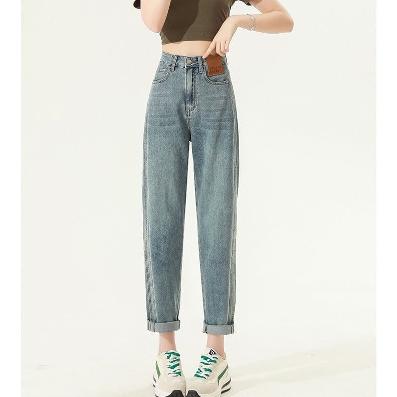 Women wearing retro blue high waist straight harem jeans with rolled cuffs and white sneakers