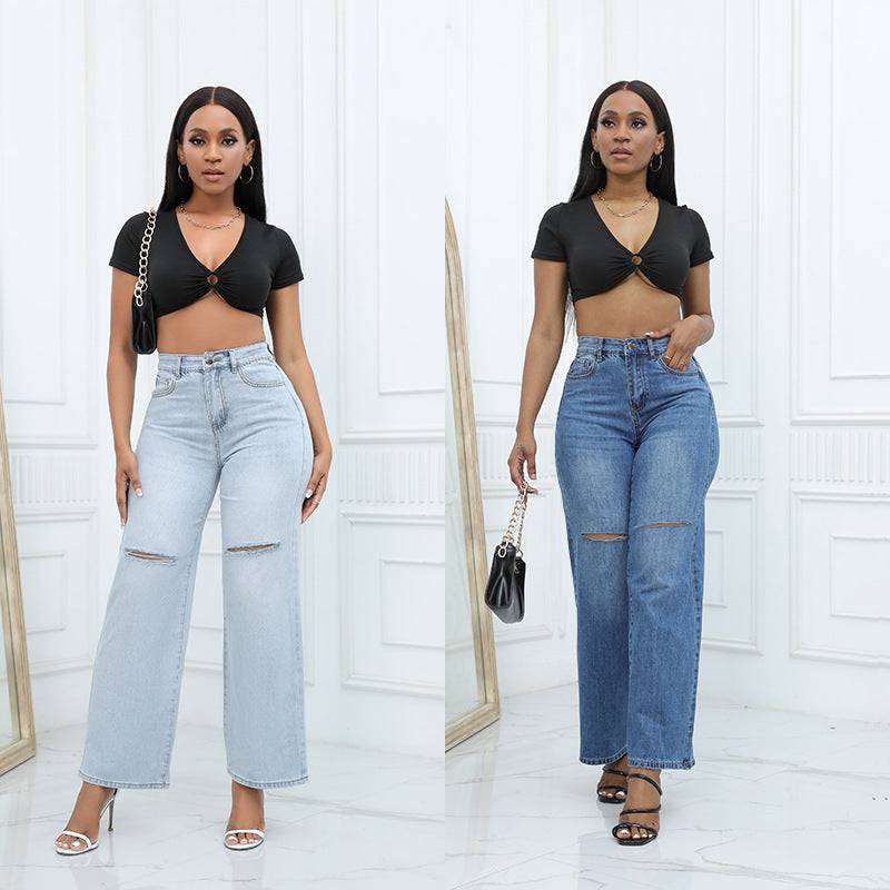 Two women wearing elegant ripped wide-leg jeans in light blue and dark blue denim with mid waist and straight-leg style paired with black crop tops in a bright white room